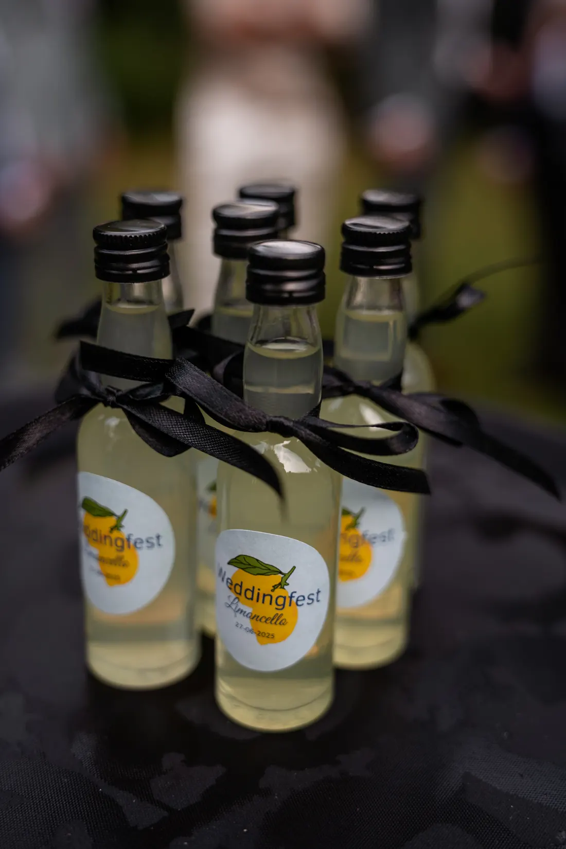 Mini-flesjes limoncello met gepersonaliseerde Weddingfest-etiketten en zwarte strikjes
