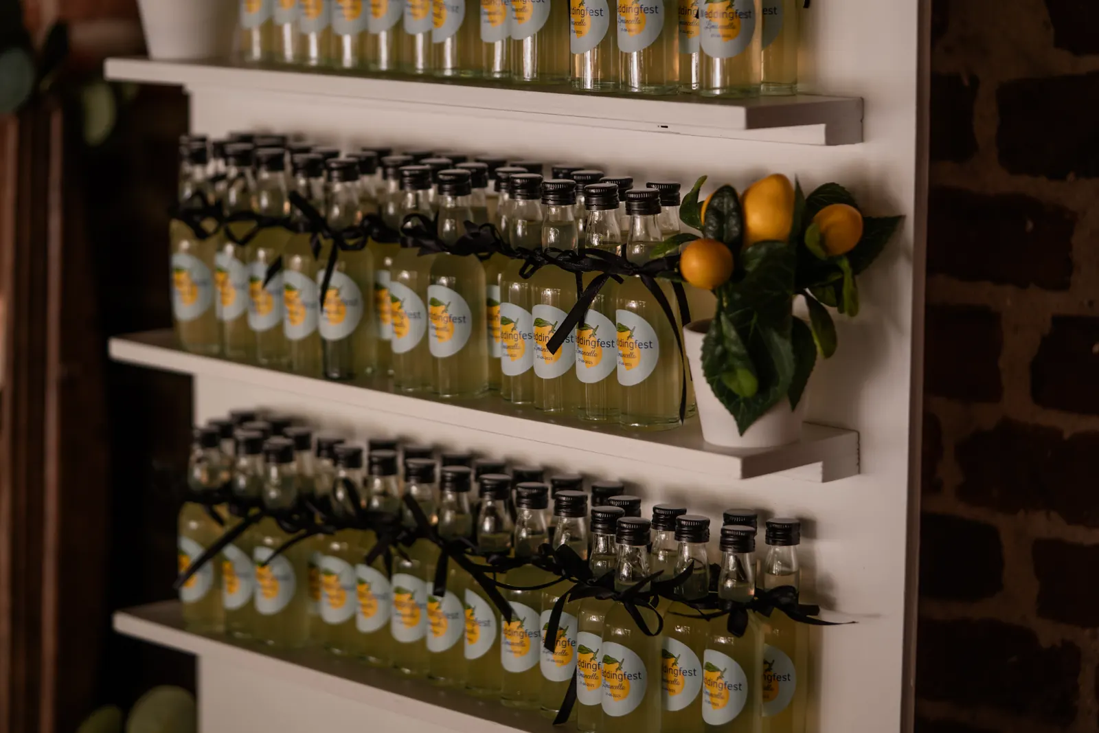 Witte Limoncello Wall vol flesjes met Weddingfest-etiketten en zwarte strikjes